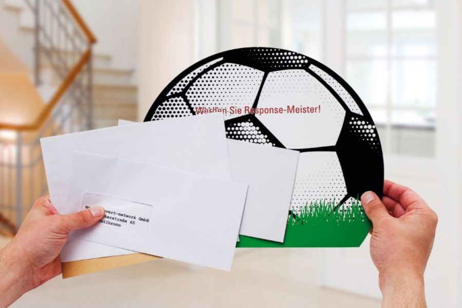 Ein Briefumschlag als Fußball gestaltet hebt sich ab vom täglichen Poststapel