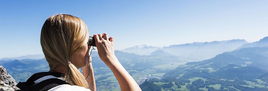 Frau blickt mit Fernglas in die Ferne