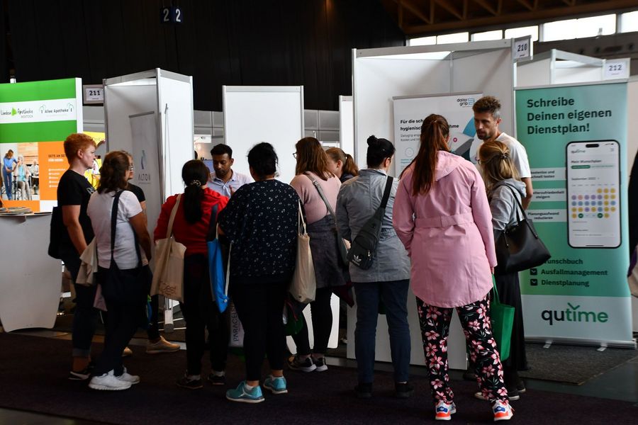 Besucherinnen und Besucher informieren sich an einem Stand über digitale Dienstplanung auf der PflegeMesse in Rostock