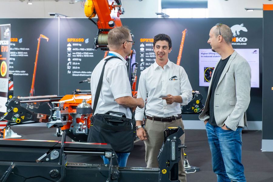 Fachgespräch an einem Messestand mit Kran- und Hebetechnik auf den Platformers' Days in Karlsruhe