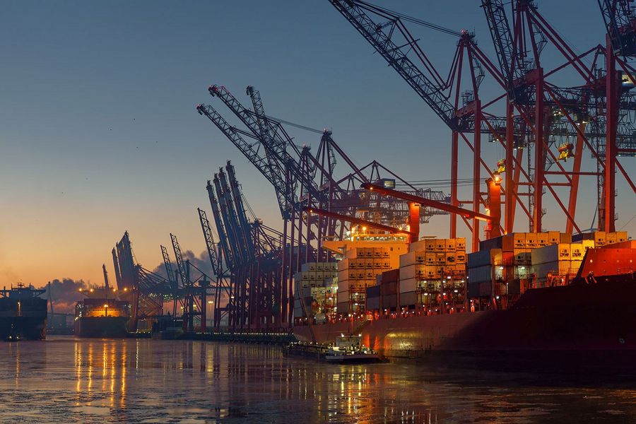 Containerlogistik und Lieferketten im Hafen Containerschiff an einem Containerterminal mit Hafenkränen bei Abendlicht