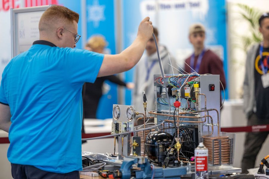 Kältetechnik im Praxiseinsatz auf der Chillventa Techniker arbeitet an einer offenen Kälteanlage mit Leitungen, Kompressor und Messinstrumenten auf der Chillventa in Nürnberg