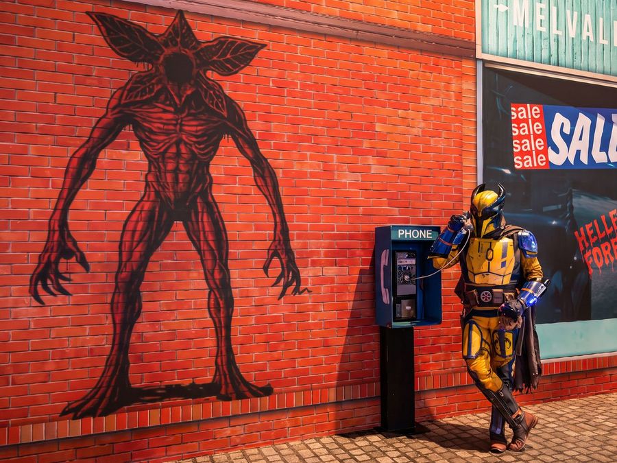 Cosplayer in gelb-blauer Rüstung vor einer inszenierten Stadtkulisse auf der gamescom