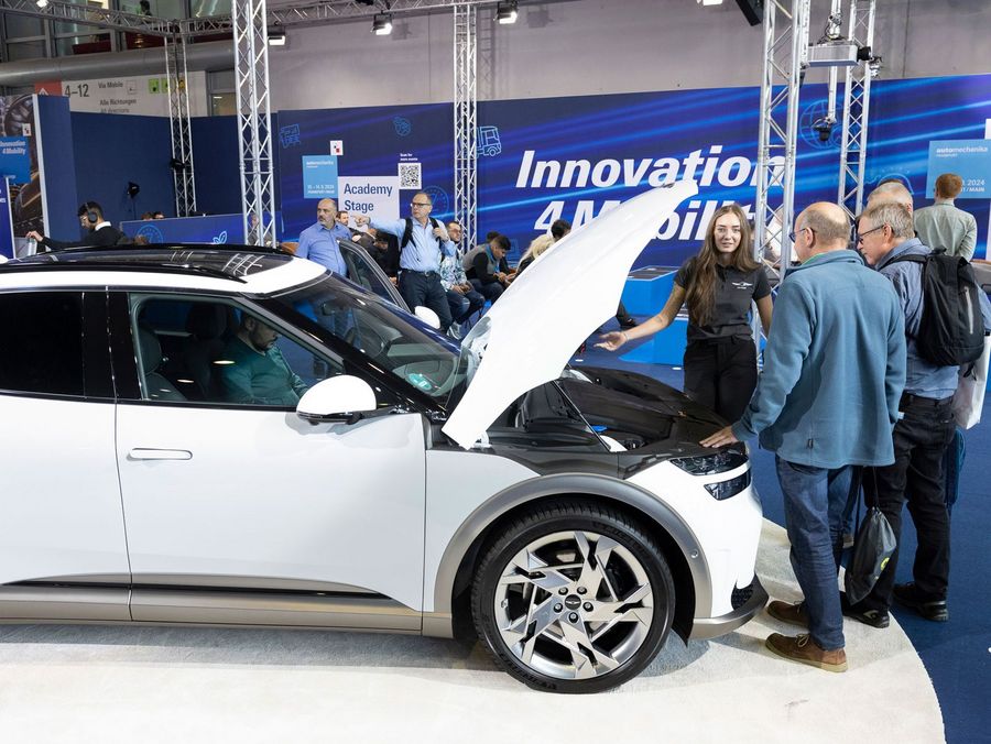 Fachbesucher informieren sich an einem Elektrofahrzeug auf der Automechanika Frankfurt