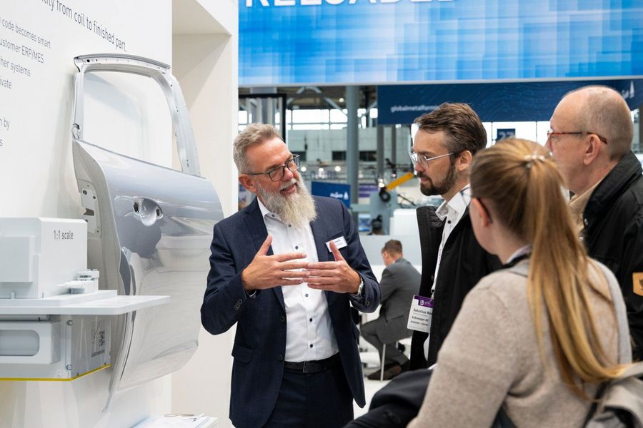 Fachbesucher im Gespräch über ein ausgestelltes Karosseriebauteil auf der EuroBLECH in Hannover
