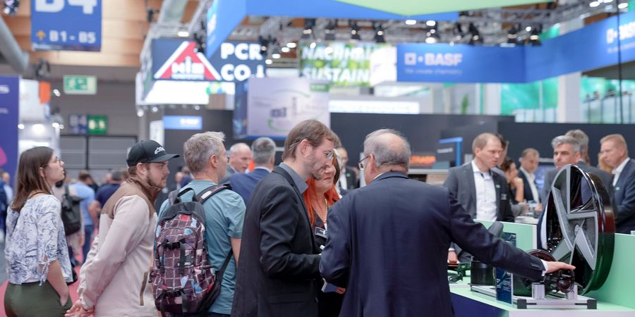 Fachbesucher auf der Fakuma in Friedrichshafen Fachbesucher im Gespräch an einem Messestand auf der Fakuma in Friedrichshafen