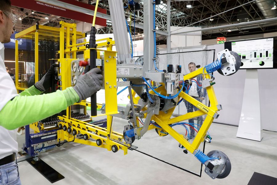 Automatisierte Glasbearbeitung auf der glasstec Mitarbeiter bedient eine technische Anlage zur automatisierten Handhabung einer Glasscheibe auf der glasstec in Düsseldorf
