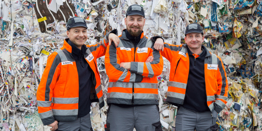 Mitarbeiter der Prinzhorn Group vor einem Berg aus Altpapier – ein Motiv, das auf Teamgeist und gelebte Kreislaufwirtschaft hinweist