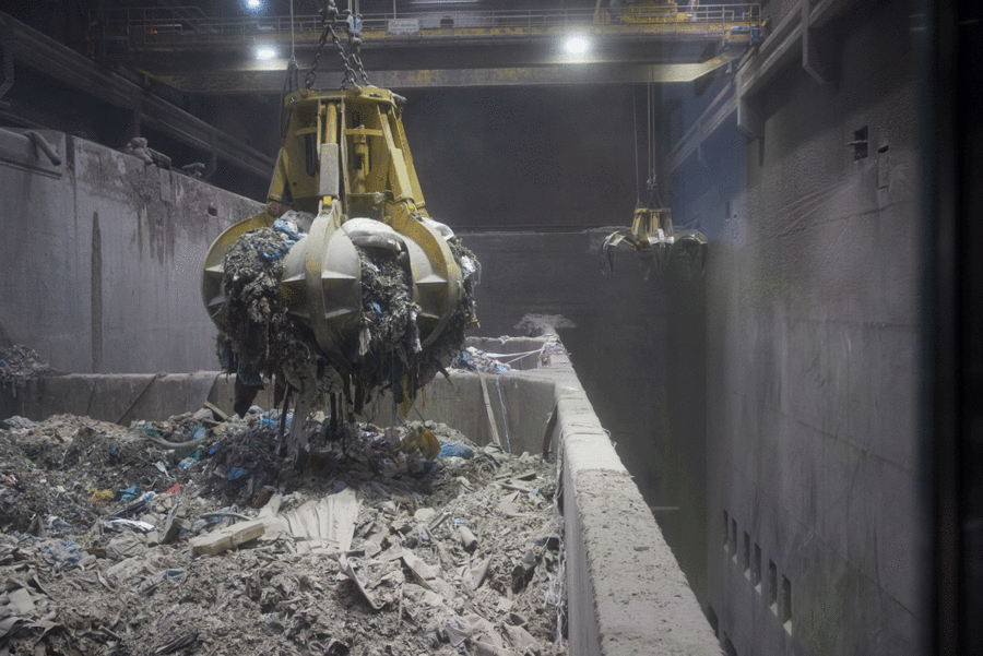 Ein Greifer transportiert Papiermaterial über einen Sammelbehälter und führt es dem geschlossenen Produktionskreislauf zu